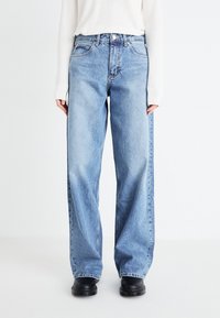 Light blue, high-waisted jeans with a loose fit, made of denim. Features front pockets, a button closure, and subtle fading.