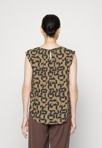 Mouwloze top met een geometrisch patroon in bruin, zwart en gedempt groen. Heeft een keyhole rug met plooien voor extra textuur.