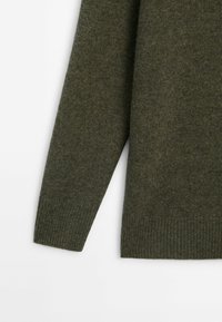 Long olive green knitted sweater sleeve with ribbed cuff and hem on a white background.