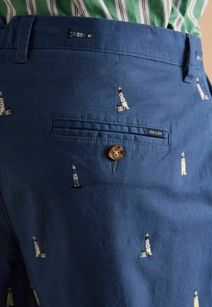 Blaue Baumwollhosen mit bestickten Leuchtturm-Mustern, einer hinteren Tasche mit Knopf und einem Joules-Label am Bund.