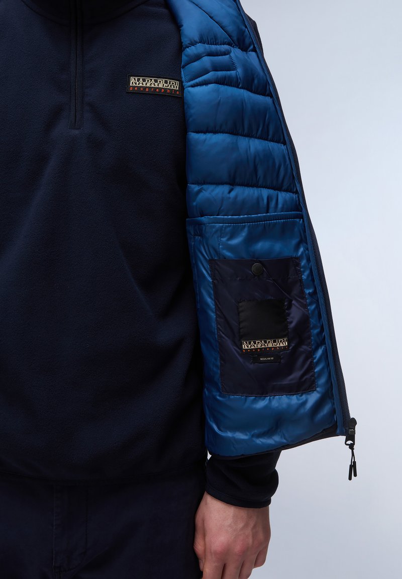 Giacca in pile navy con maniche in nylon blu, tasca con zip e patch logo. Design a pannelli con tessuto testurizzato.