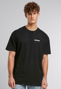 Schwarzes Baumwoll-T-Shirt mit kurzen Ärmeln, rundem Ausschnitt und weißem Drucklogo "DEFSHOP" auf der Brust. Lässige, entspannte Passform.