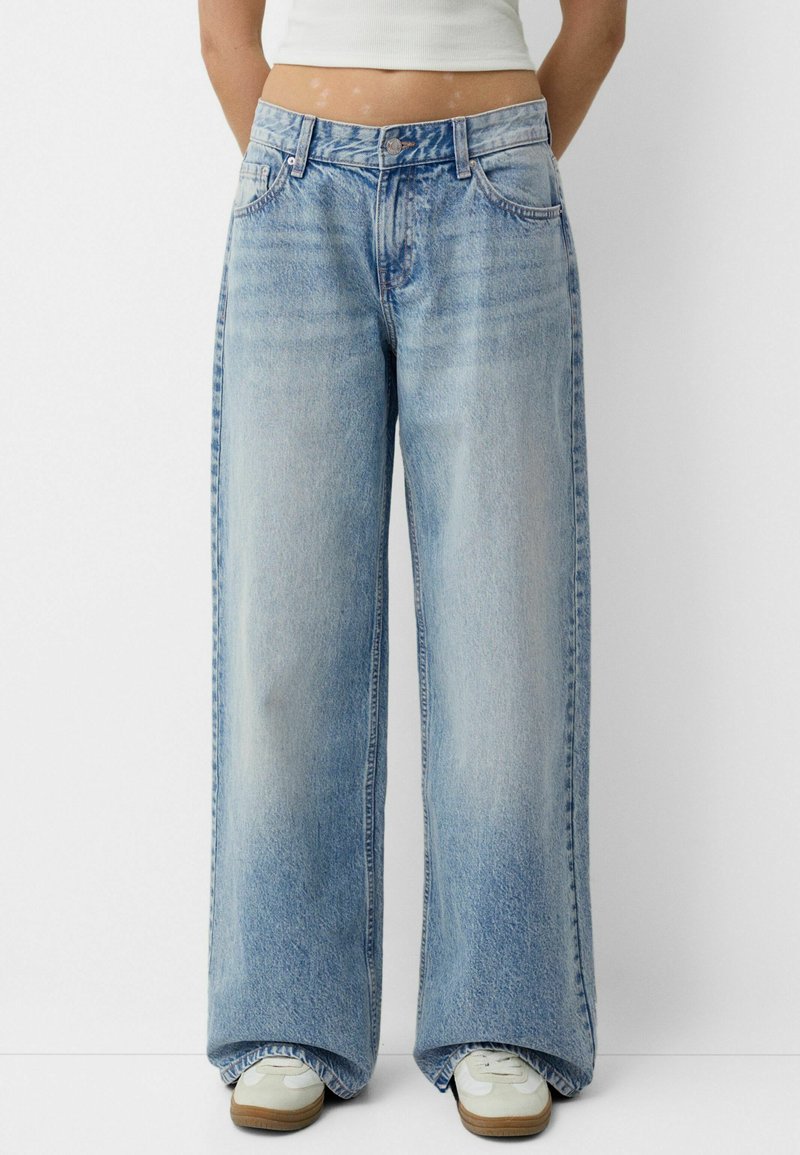 Jeans largi de un albastru deschis, cu un aspect decolorat, având bucle pentru curea, cinci buzunare și o închidere cu nasture. Finisate cu un tiv brut și ușoare distrugeri.