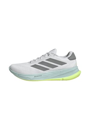 Baskets de sport blanches avec tige en mesh, accents gris et semelle verte. Présente un logo à trois bandes et un design de semelle texturé pour une meilleure traction.