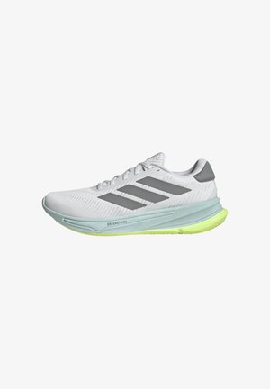 Weißer Sportschuh mit Mesh-Obermaterial, grauen Akzenten und grüner Sohle. Verfügt über das Logo mit drei Streifen und ein strukturiertes Sohlen-Design für Traktion.