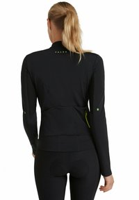 Veste de sport noire avec manches longues, col haut et panneaux en mesh sur les côtés. Présente un logo vert discret et une poche zippée dissimulée.