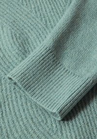 Helles blaues Wollstrickkleid mit einem strukturierten, gerippten Muster und glatten Bündchendetails, das insgesamt weich und gemütlich wirkt.