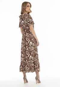Bruine en witte gemêleerde midi-jurk met korte mouwen, geplooide taille en geribbelde zoom, gecombineerd met beige stilettos.