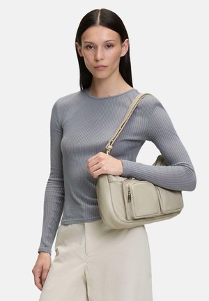 Borsa a spalla in pelle beige con molteplici tasche con zip; texture liscia; forma morbida e arrotondata; indossata con un top grigio a coste aderente.
