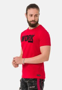 Rotes Baumwoll-T-Shirt mit großem schwarzen "WORK"-Grafikdesign auf der Vorderseite, Rundhalsausschnitt, kurzen Ärmeln und schlanker Passform.