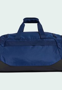 Bolsa de lona azul marino hecha de tela duradera, con dos asas reforzadas, cierre de cremallera y un panel inferior negro para mayor estabilidad.