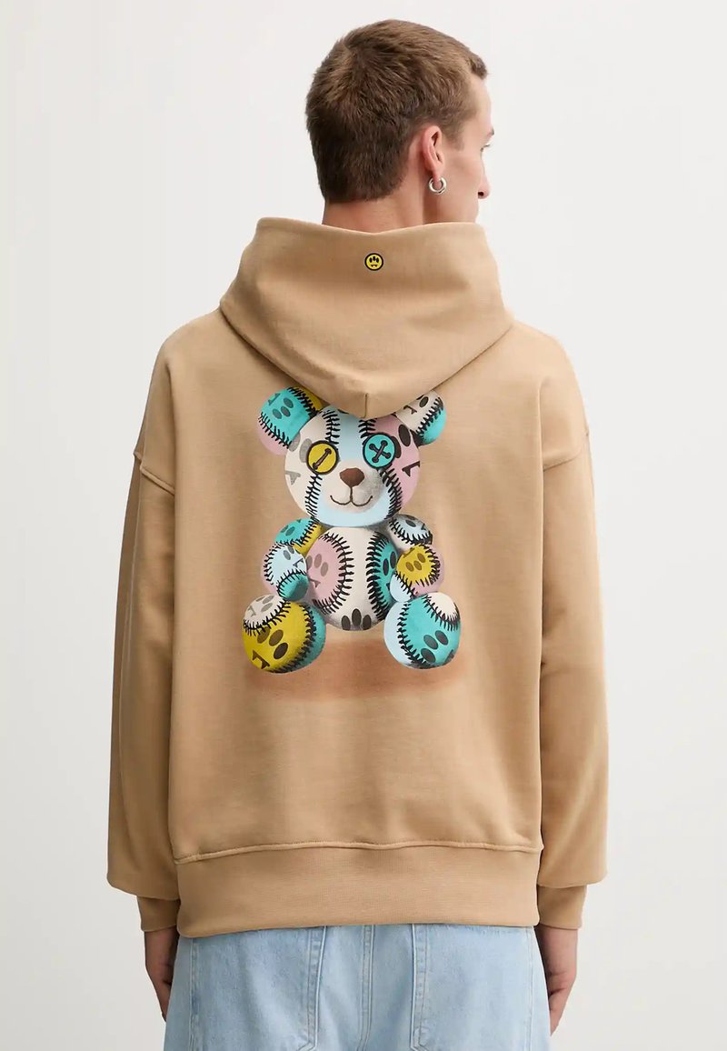 Sudadera con capucha en color marrón claro, con un gráfico colorido de un oso de peluche en la parte posterior, que presenta varios patrones circulares y acentos en colores pastel.