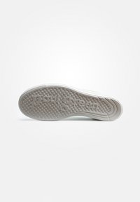 Suola di una sneaker con una superficie in gomma texturizzata, nome del marchio "Paul Green" in rilievo, forma arrotondata e colore grigio chiaro con sottili accenti verdi.