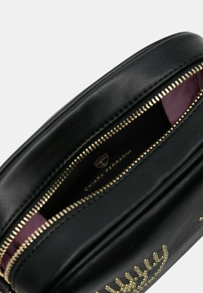 Borsa in pelle nera con zip dorata e fodera interna rosa chiaro. Caratterizzata da logo del marchio impresso all'interno. Forma compatta e ovale.