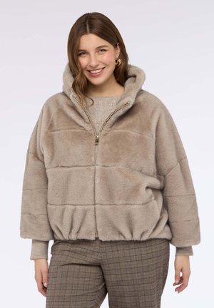 Giacca beige con zip realizzata in un materiale morbido e testurizzato simile alla pelliccia, con cappuccio, cuciture orizzontali e orlo elastico.