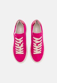 Lysrosa mockasins i suède med beige snörningar, rund tå, platt gummisula och metalliska detaljer vid hälen. Texturen ser slät ut.