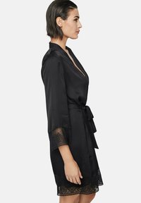 Robe en satin noir avec une bordure en dentelle aux manches et à l'ourlet. Dispose d'un décolleté en V profond, de manches courtes et d'une ceinture à la taille pour la fermeture.