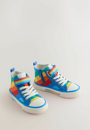 Színes magas szárú sportcipők foltmintás kialakítással kék, piros, sárga és zöld színekben, cipzárral és fehér gumitalppal.