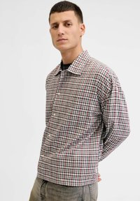 Camicia a quadri in tessuto leggero con colori rosso, nero e bianco; colletto button-down; taschino sul petto; vestibilità rilassata.