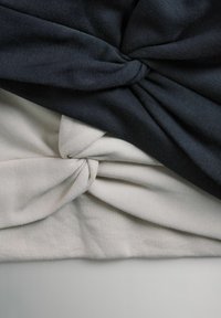 To stykker stof: et mørkeblåt og et lysegråt, begge med et snoet knudedesign. Blød tekstur, bomuldsblandet materiale.