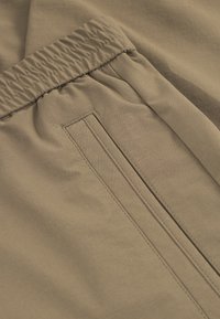 Khaki kalhoty s elastickým pasem, s hladkým povrchem a skrytou boční kapsou s pečlivě sešitými detaily.