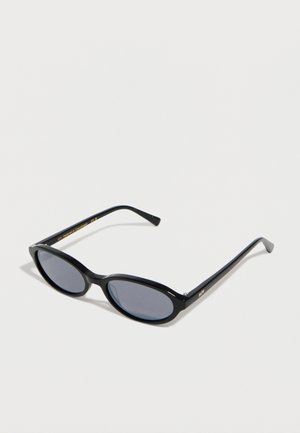 Gafas de sol con montura ovalada negra, lentes tintadas oscuras, varillas delgadas y letras doradas sutiles en la parte interna de la varilla y en la esquina frontal.