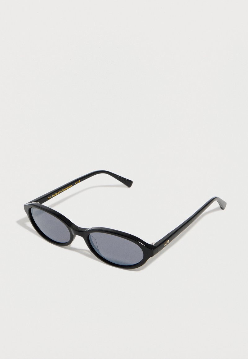 Μαύρα γυαλιά ηλίου με οβάλ σκελετό, σκούρους φακούς, λεπτά βραχίονες και διακριτικά χρυσά γράμματα στο εσωτερικό του βραχίονα και στη μπροστινή γωνία.