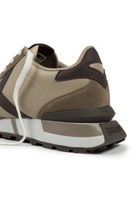 Zapatillas beige y marrón que combinan ante y piel, con una suela acolchada y un acento marrón con un logo en el talón.