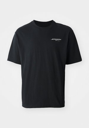 Black cotton t-shirt with a crew neck, short sleeves, relaxed fit, and white logo text on the left chest area. No patterns or accents.