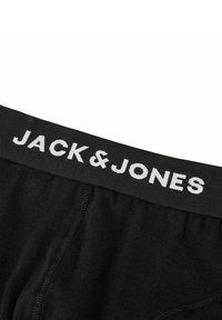 Schwarze Baumwoll-Boxershorts mit einem breiten schwarzen Bund, auf dem der Markenname "JACK & JONES" in weißer Schrift zu sehen ist. Glatte Textur, figurbetontes Design.