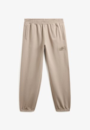 Beige sweatpants with elastic waistband, side pockets, tapered legs, and embroidered logo detail on the left thigh. Smooth fabric texture.