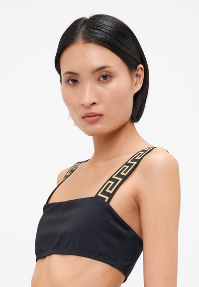 Czarny crop top z szerokimi ramiączkami z złotym geometrycznym wzorem. Gładki materiał z dopasowanym krojem i kwadratowym dekoltem.