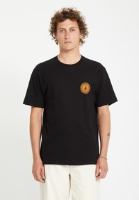 Sort bomulds t-shirt med korte ærmer. Har en lille, orange solskin grafik på venstre bryst. Standard rund hals design.