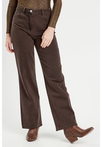 Bruine denim hoge taillebroek met rechte pijpen, vijf zakken en een knoopsluiting, gecombineerd met bruine haklaarsjes tot de enkel.