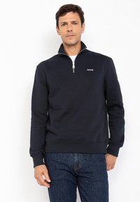 Felpa zip-up blu navy in cotone, con collo alto, polsini a coste e un piccolo logo rosso sul petto.