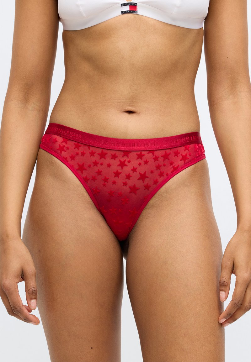 Κόκκινο διαφανές στρινγκ με μοτίβο από αστέρια, διαθέτει άνετη ζώνη μέσης με το όνομα της μάρκας. Ελαφρύ και εφαρμοστό σχέδιο.