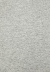 Tejido de punto gris claro con una textura suave, que presenta un sutil patrón jaspeado a lo largo y una costura uniforme.