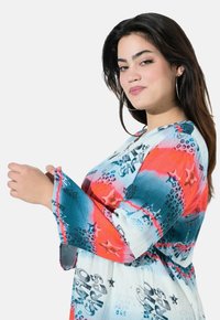 Langærmet kjole i multicolor, med et gradientmønster i blå, rød og hvid, samt grafiske prints og flagrende mansjetter.