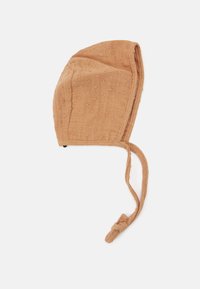 Boné infantil castanho claro feito de tecido texturizado com pequenos pontos elevados. Apresenta laços para um fecho seguro no pescoço.
