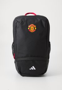 Svart ryggsekk med røde detaljer, med Manchester United-logoen på fronten, netting side lommer, og Adidas-logoen nederst.