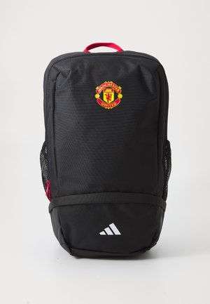 Mochila negra con acentos rojos, que presenta el logo del Manchester United en la parte frontal, bolsillos laterales de malla y un logo de Adidas en la parte inferior.