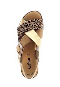 Beige sandals with crossed straps and leopard print at the top. Features a buckle and cushioned insoles. Smooth texture and rounded shape.