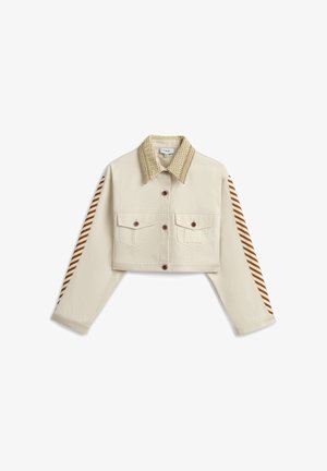 Chaqueta corta beige con cuello de punto, detalles a rayas marrones y blancas en las mangas, cierre con botones al frente y dos bolsillos en el pecho con botones.