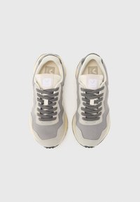 Light gray athletic shoes with a mesh upper, textured fabric detailing, and a cream rubber sole. Features gray laces and a branded tag.
