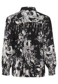 Zwarte blouse met een wit en grijs bloemmotief, met een kraag, puffed mouwen en geplooide details bij de manchetten en op de rug.
