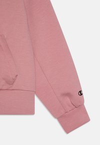 Felpa rosa chiaro con tasca sul davanti, polsini a costine e un piccolo logo nero sulla manica. Tessuto in morbido cotone misto.