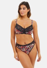 Conjunto de bikini negro con estampado floral que incluye un bralette con ribete de encaje y tirantes ajustables, acompañado de una parte inferior de cintura baja con acentos florales.