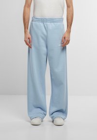 Light blue sweatpants with a relaxed fit, elastic waistband, and side pockets. Made from soft fabric, featuring subtle logo detailing.