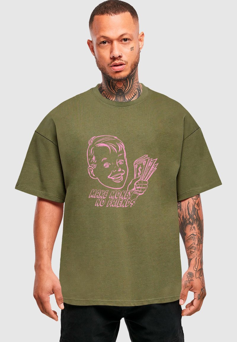 Olivově zelené oversized tričko vyrobené z bavlny, se růžovou grafikou postavy držící peníze a textem "VYDĚLEJ PENÍZE, ŽÁDNÍ PŘÁTELÉ."
