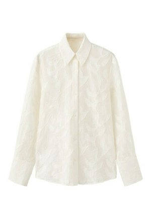 Camisa blanca de manga larga con botones y cuello puntiagudo, con un sutil patrón de hojas en la tela.